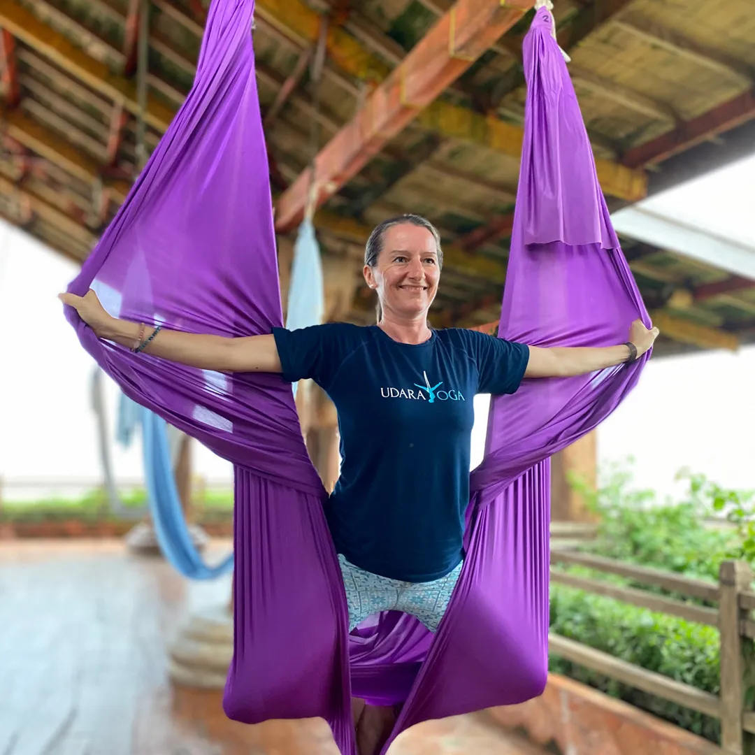 Instructor demonstrating an inverted pose in the aerial yoga teacher training at Udara Bali